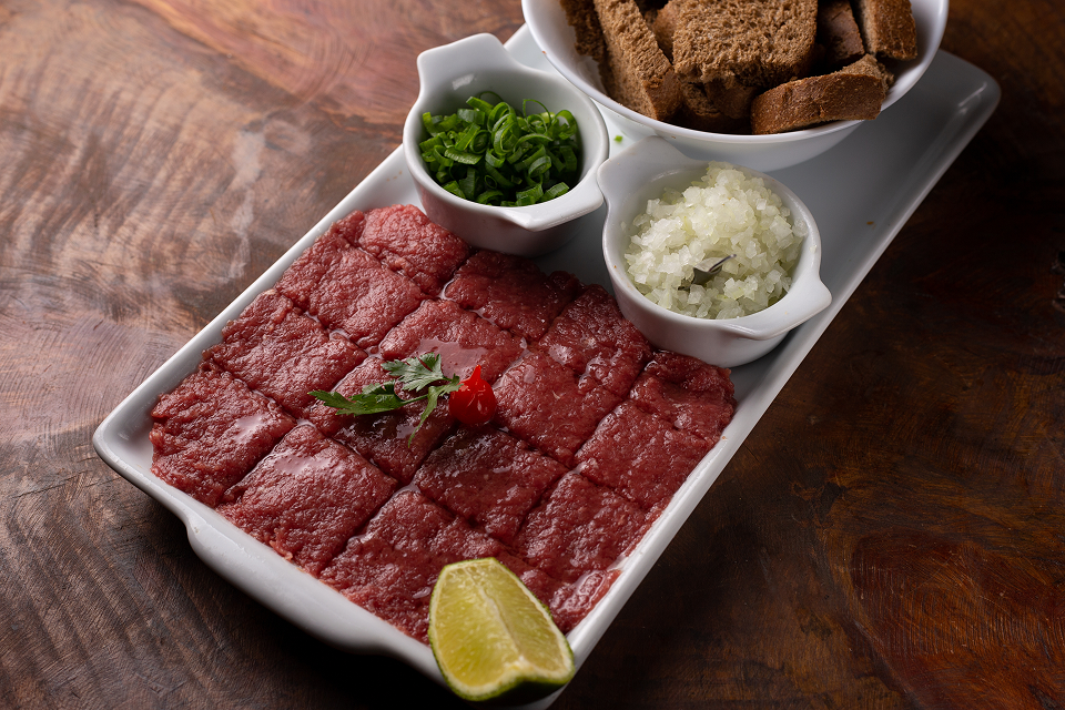 Carne de onça, prato típico de Curitiba preparado com carne bovina crua temperada e servido sobre broa de centeio.