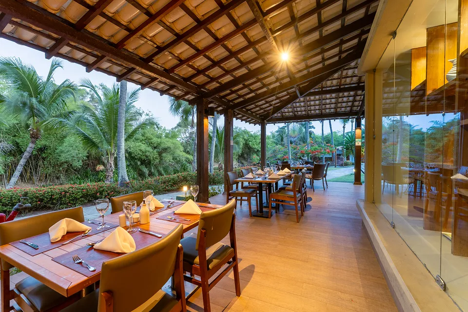 Ambiente do restaurante do Hotel Deville Prime Salvador com mesas e vista para a área externa.