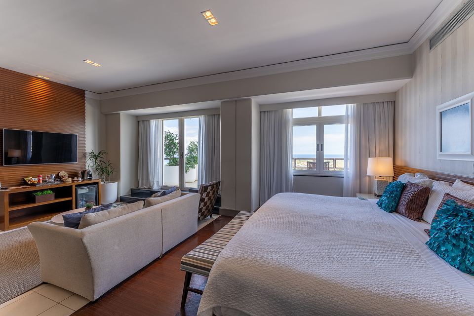 Quarto do Hotel Deville Prime Salvador com cama e ambiente de estar.